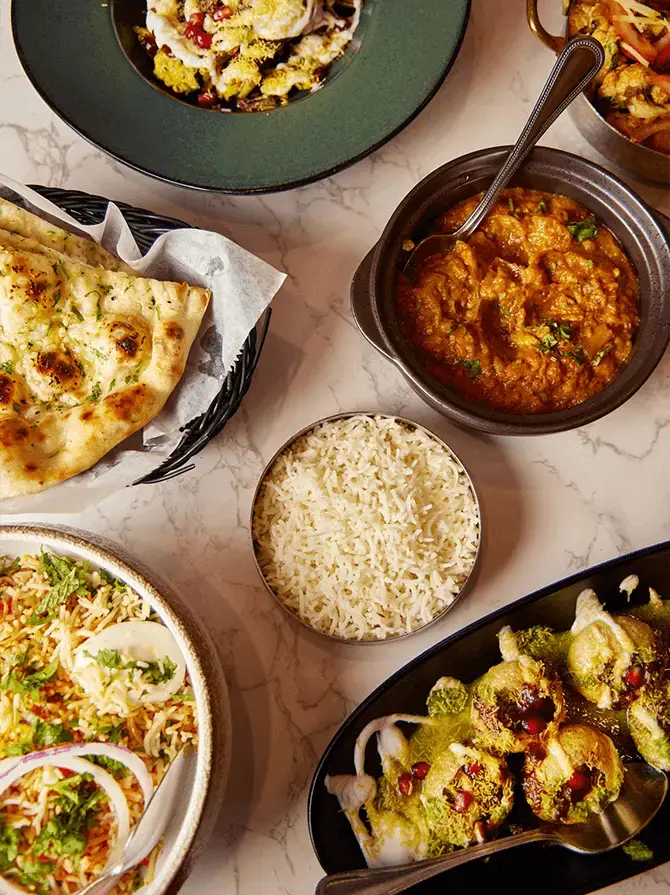 Naan, curry, rice and chaat laid out on a marble table